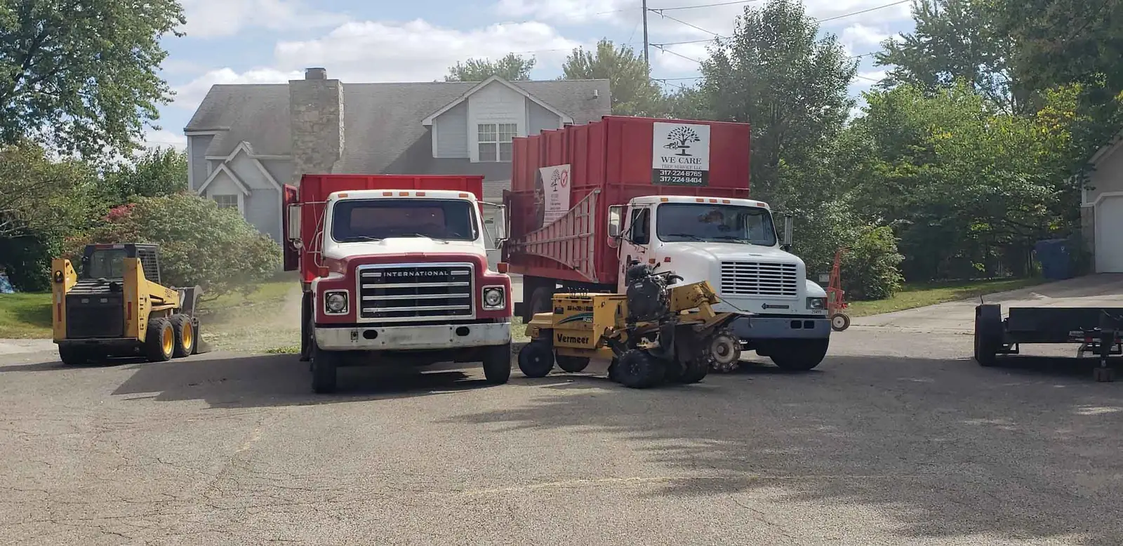 Tree service trucks, skid steer and stump grinder parked on a residential street in Indianapolis